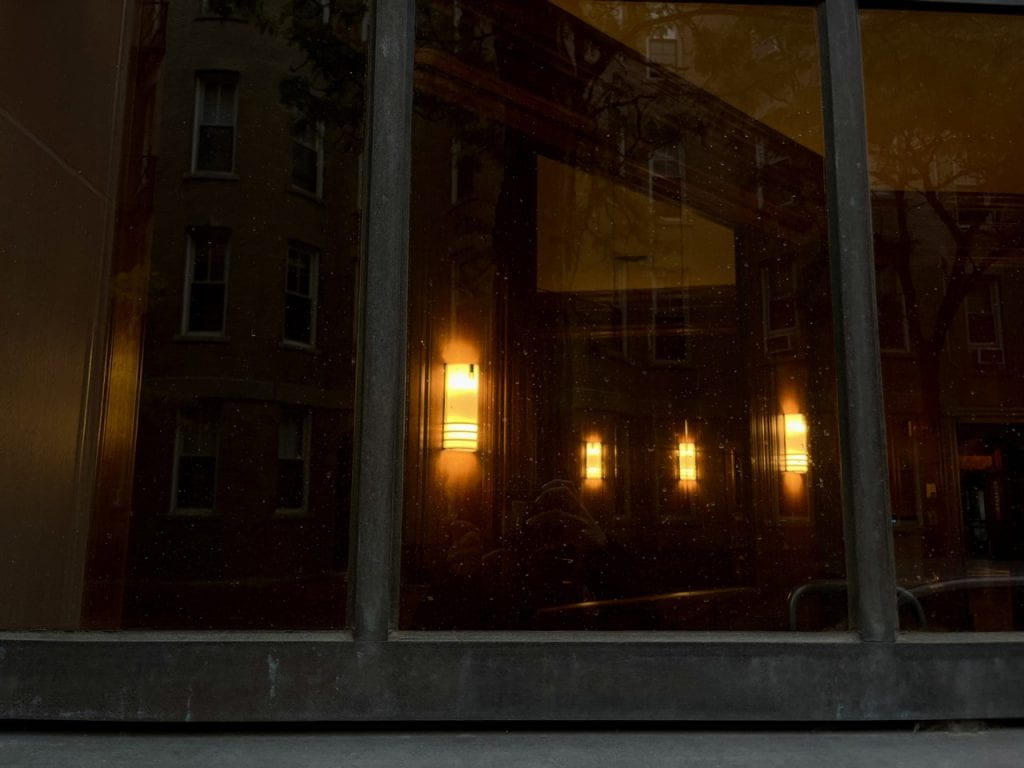 lights reflecting in dark windows on a city street