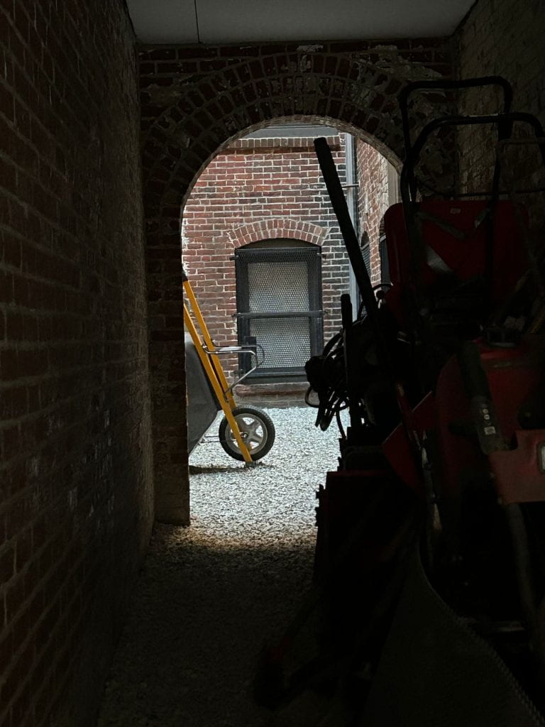 view down a narrow alley with gardening equipment