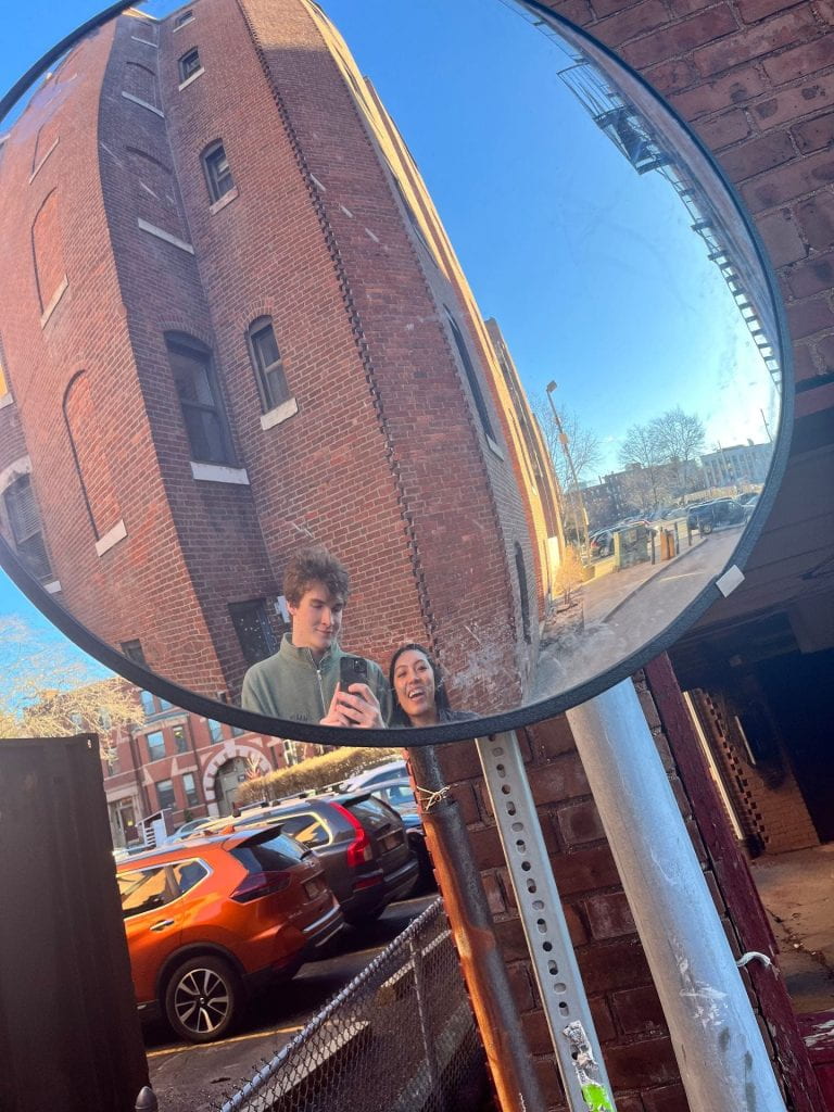 reflection of two people in a street sign mirror