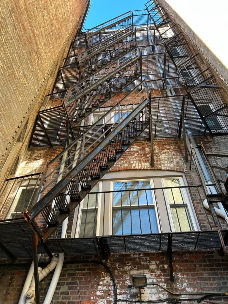 metal fire escape along the back of a brick building in an alleyway