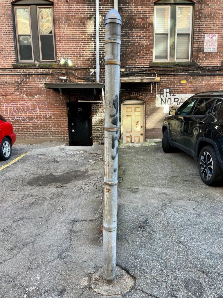 chain link fence post and car parking area behind a brick building